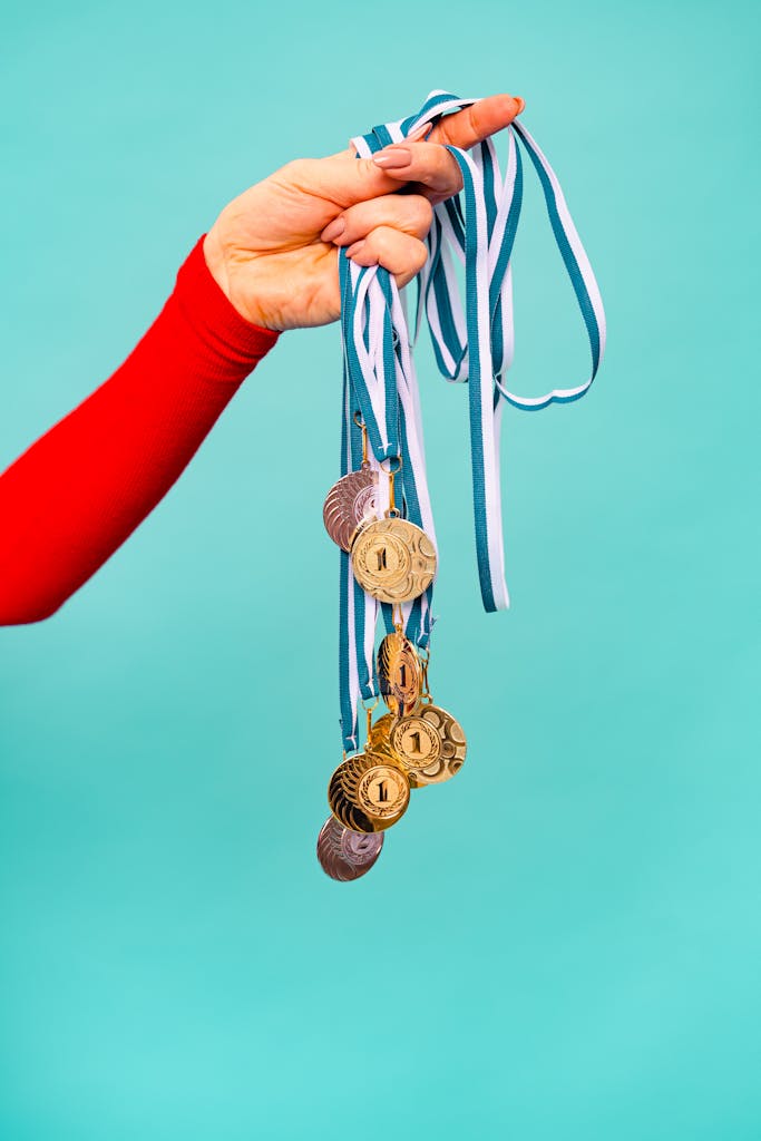 A hand holds several gold medals with ribbons, symbolizing achievement and victory.